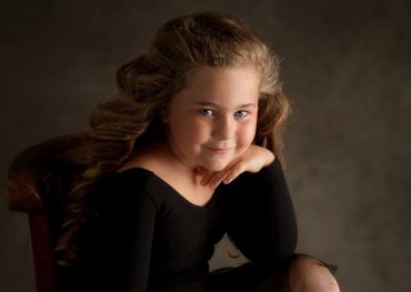 Young girl with long wavy hair smiling gently.
