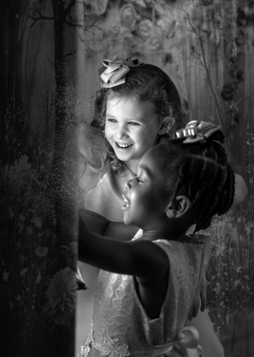 Two young girls with bows, joyfully playing.
