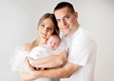 Happy family with newborn baby in white.