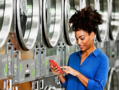 Young woman using smartphone to start dryers at Mary’s Laundromart.
