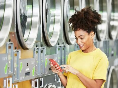 Young woman using smartphone at laundromat.