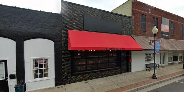 Black brick restaurant storefront with red awning