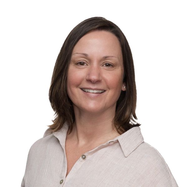 Smiling woman in a light beige blouse against a white background.