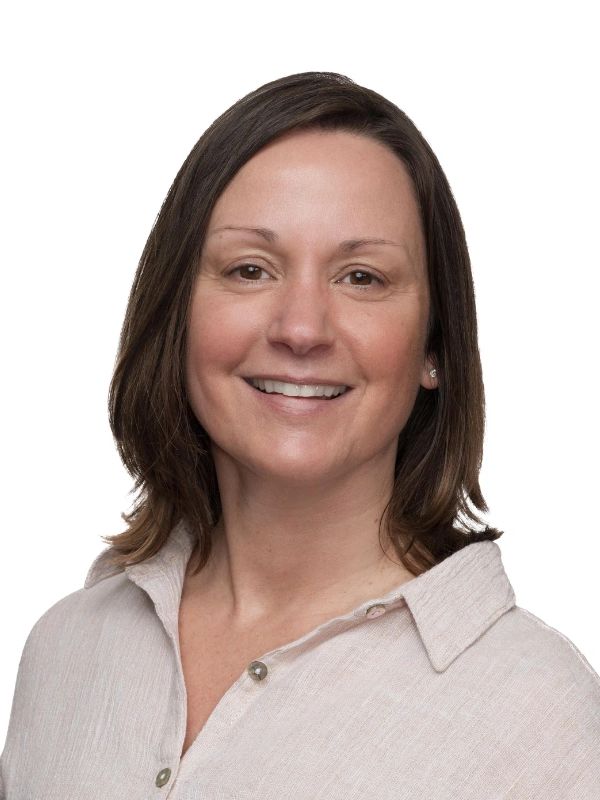 Smiling woman in a light beige blouse against a white background.
