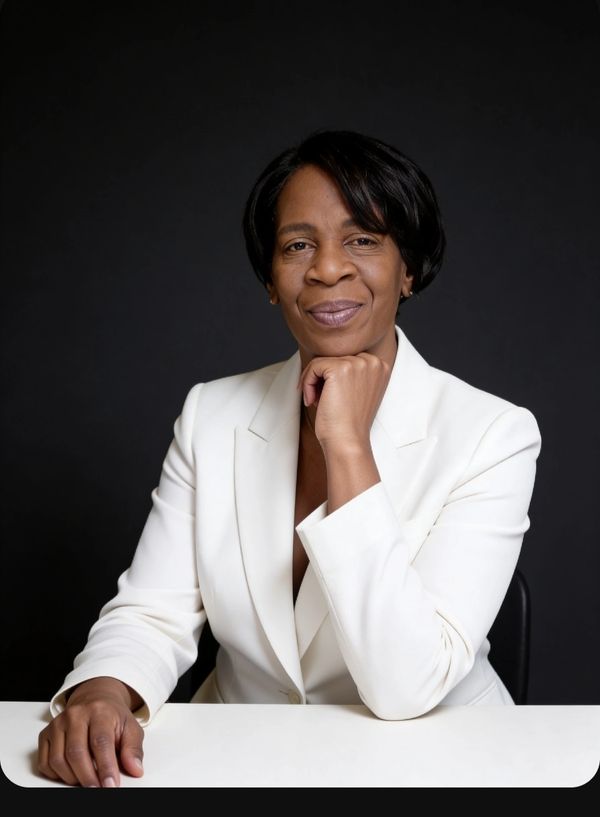 Confident woman in a white blazer poses against a black background.