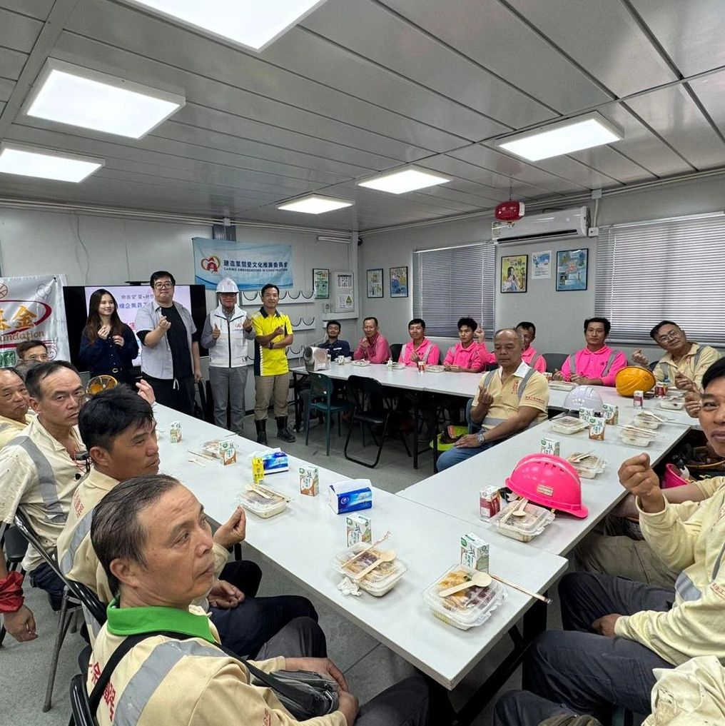 Group of workers and staff gathered around tables with meals in a meeting room.