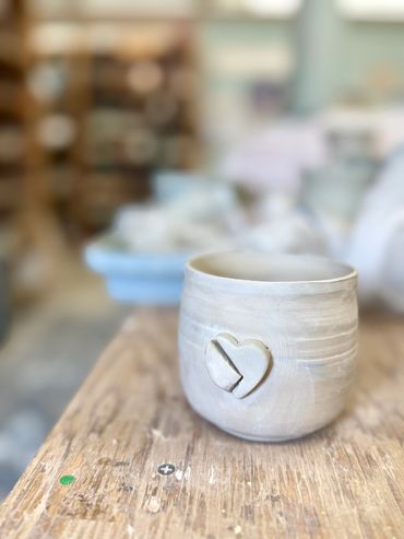 White ceramic cup with heart design on wooden table.