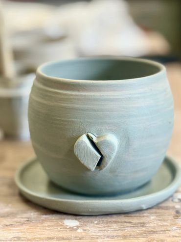 Handcrafted ceramic pot with a small heart design.