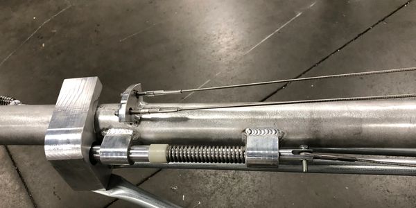 Close-up of a metal cylindrical mechanical component with cables and springs.
