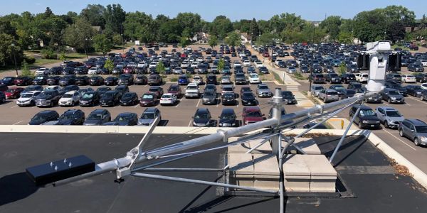 Metal structure on a rooftop with a large parking lot in the background.