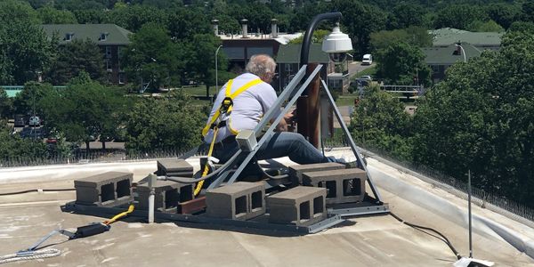 Man secured with a harness working on a rooftop installation.