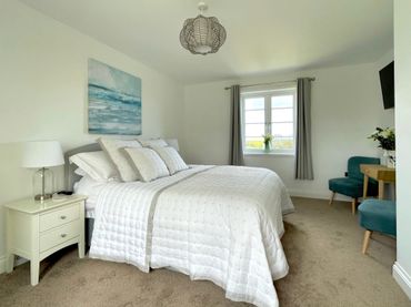 a beautiful bedroom with comfortable bed and luxurious bedding, with views to the sea
