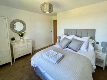 a beautiful bedroom with comfortable bed and luxurious bedding, with views to the sea