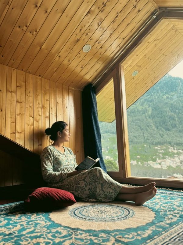 Woman reading by a large window with mountain view.