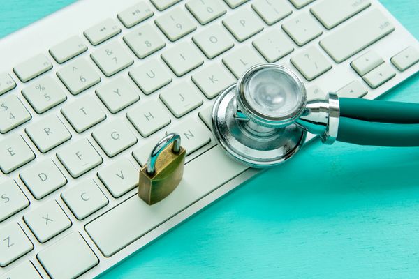 Stethoscope and padlock on keyboard symbolizing cybersecurity in healthcare.