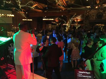 A lively indoor party with people dancing and a singer on stage.