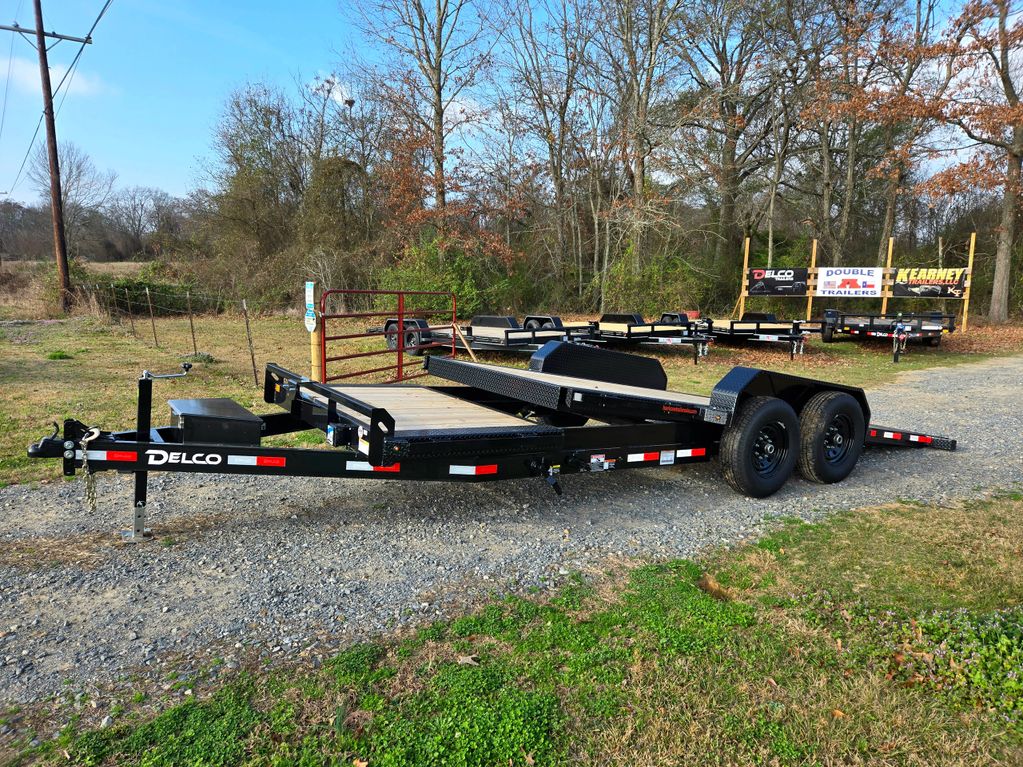 Black Delco flatbed trailer parked on a gravel path outdoors.