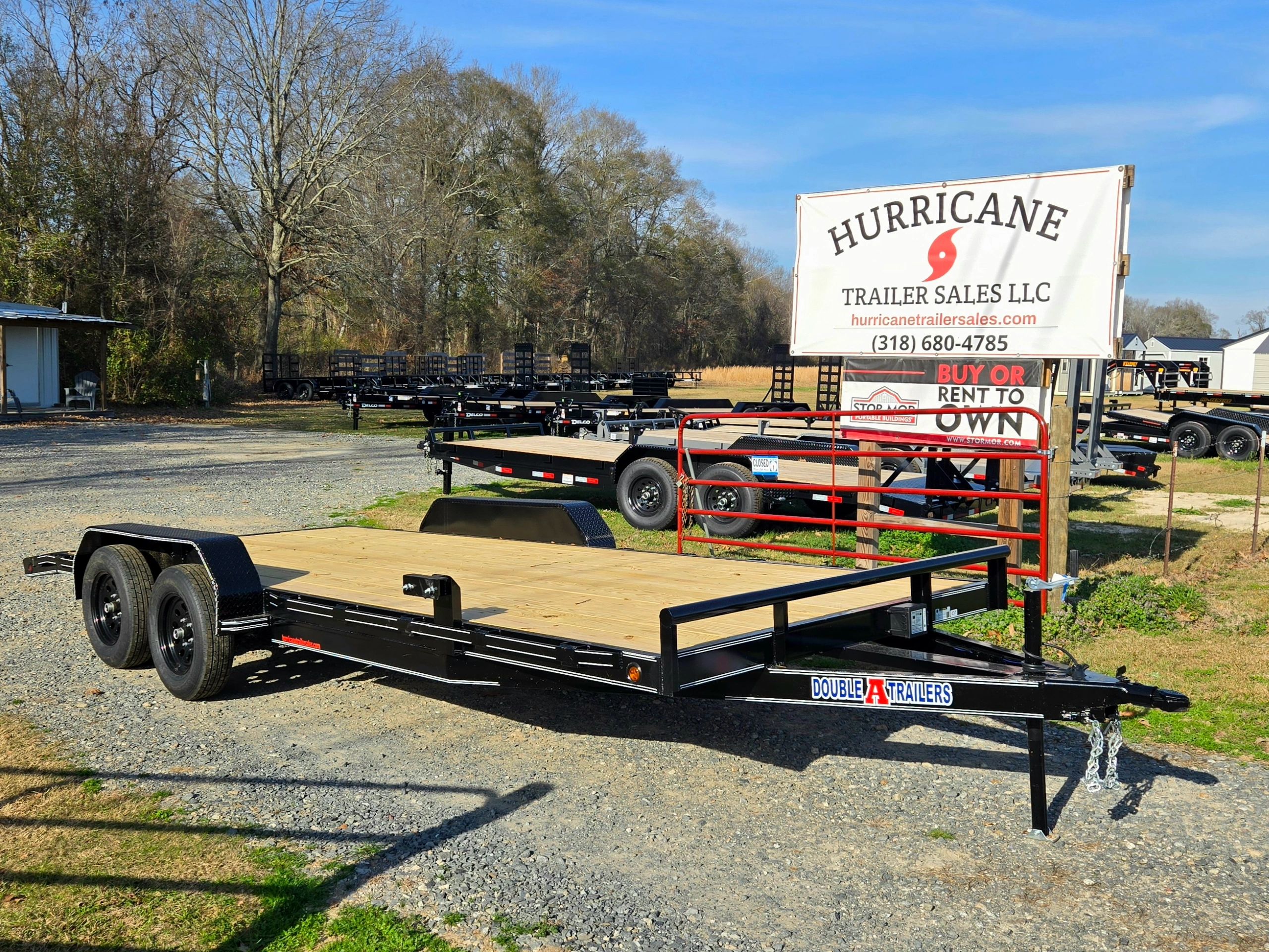 Black flatbed trailer displayed at Hurricane Trailer Sales lot on a sunny day.