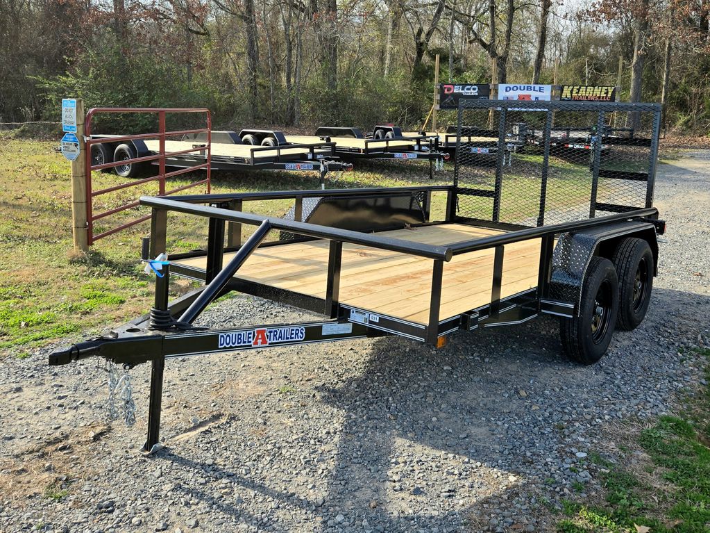 Black utility trailer with wooden floor on gravel, surrounded by trees and other trailers.