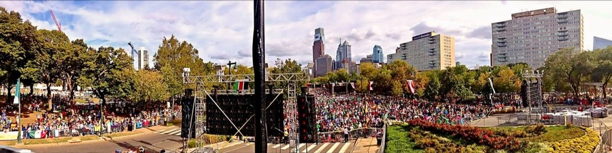 Large crowd gathered at an outdoor event in a city park with skyscrapers in the background. Philadelphia. Pope Francis. Festival of Families.