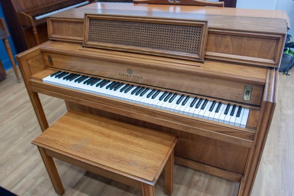 Wooden upright piano with matching bench.