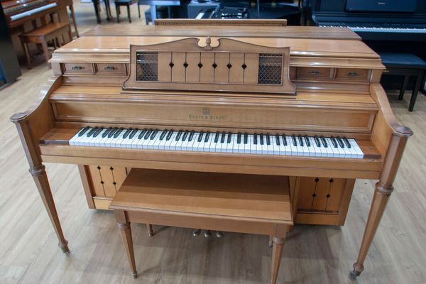 Vintage wooden upright piano with matching bench.