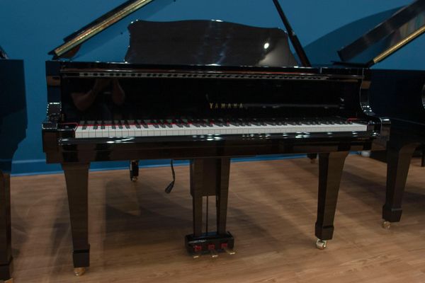 A black Yamaha grand piano on a wooden floor.