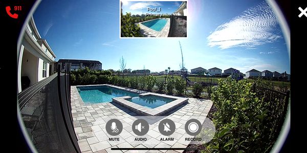 View of a backyard pool and spa captured by a security camera with control icons.