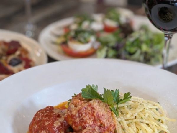 Plate of spaghetti with meatballs and a glass of red wine.
