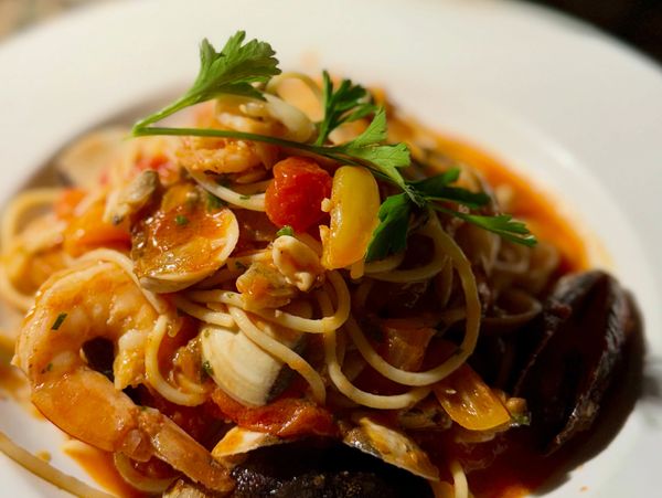Seafood pasta garnished with fresh parsley on a white plate.