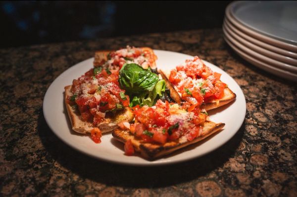 Plate of bruschetta with diced tomatoes and basil on toasted bread.