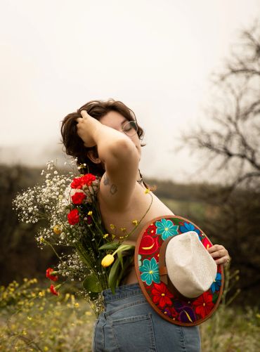Person with flowers and colorful hat in nature.