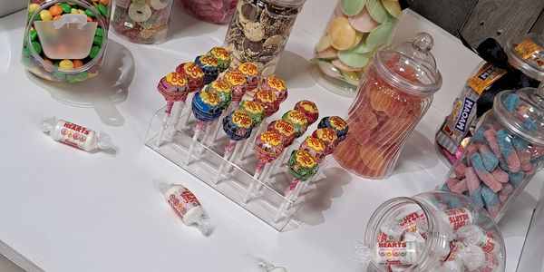 Colorful lollipops and various candies displayed on a white table.
