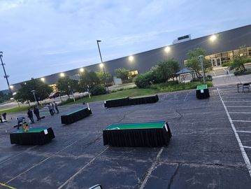 Outdoor setup with tables covered in black cloth in an parking lot.