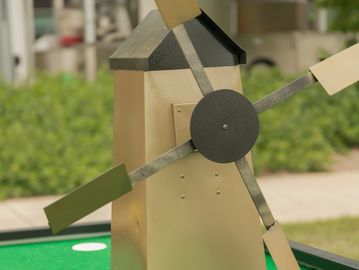 Model windmill with rotating blades outdoors.