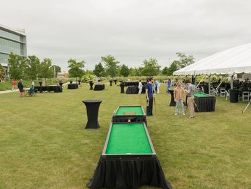 Outdoor event setup with games and tables on grass.