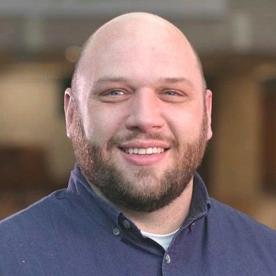 Smiling bald man with beard in blue shirt.