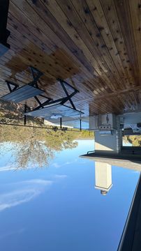 Spacious wooden deck with outdoor grill and picnic table under clear blue sky.