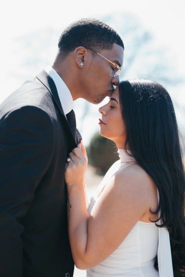 A man tenderly kisses a woman's forehead in an intimate moment.