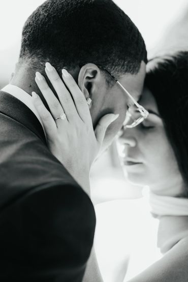 Close-up of a couple sharing an intimate moment, highlighting an engagement ring.