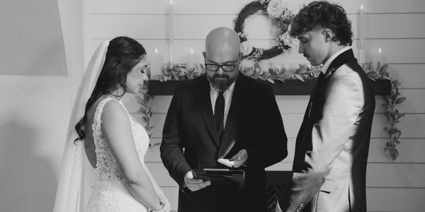 A bride and groom stand before an officiant during their wedding ceremony.