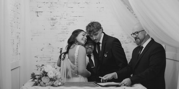 A joyful newlywed couple shares a moment with the officiant during their wedding ceremony.