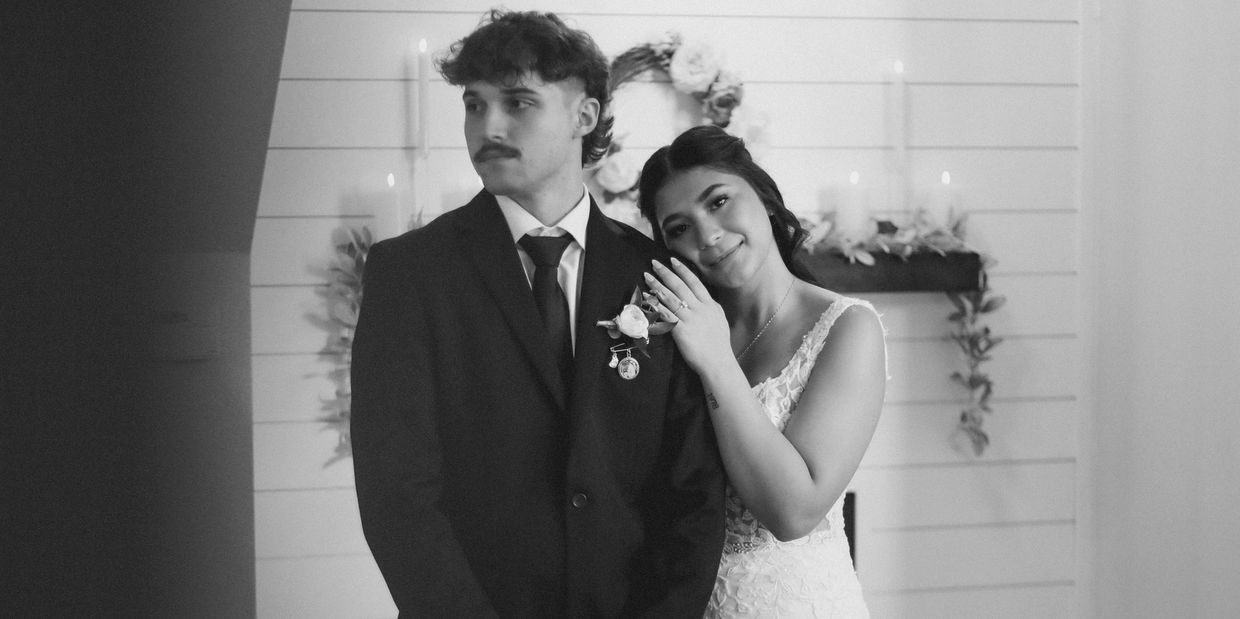 Bride leaning on groom's shoulder during wedding ceremony.