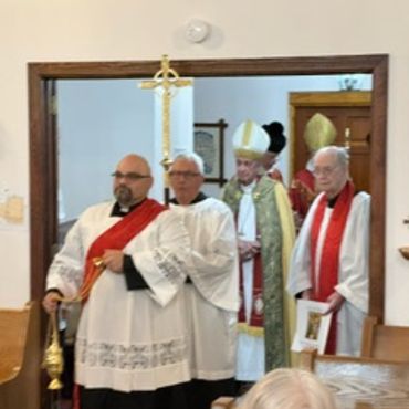 Clergy members in ceremonial robes standing in a church doorway.