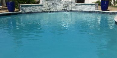 A calm swimming pool with a water feature.