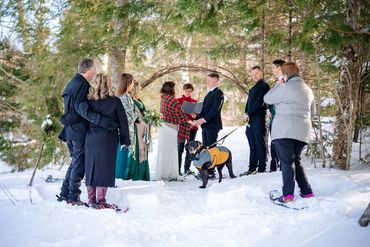 Ontario Wedding Officiant marrying a couple in a snowy forest wearing snowshoes as guests watch.