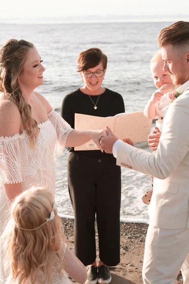Bride, groom, Justice of Peace and small children getting married on a Nova Scotia beach at sunset.