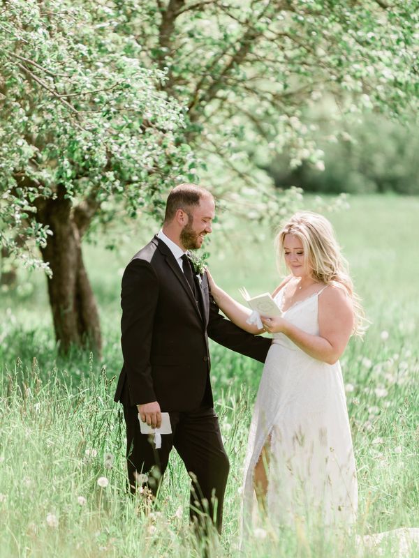 Bride and groom exchanging vows in a grassy meadow in Nova Scotia.