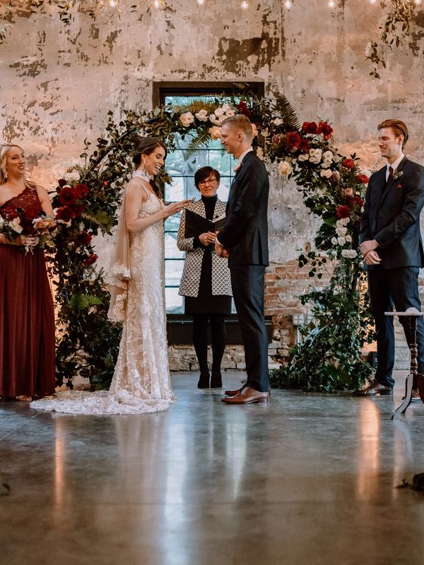 An Ontario Officiant marrying a couple in front of a floral arch.