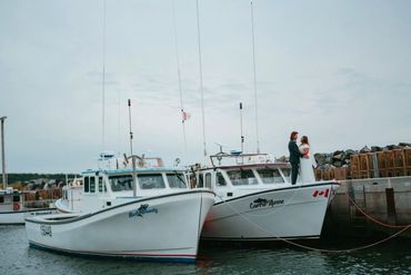 Nova Scotia elopement showing a bride and groom standing on a lobster boat in a fishing wharf.